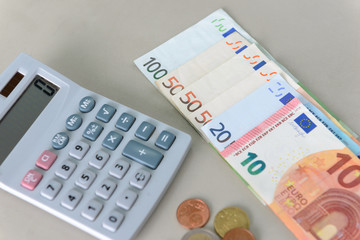 Euro money banknotes and coins counting with calculator on desk