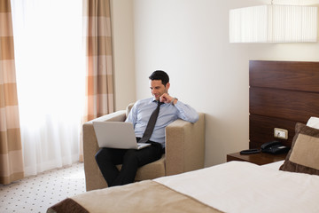 Business man using laptop in hotel room.