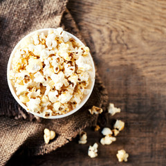 Salt popcorn in a red cardboard box on the wooden table, Cinema concept.