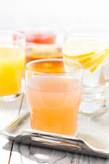 fresh citrus juices in glasses on white table, vertical