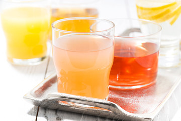 fresh citrus juices in glasses on white table