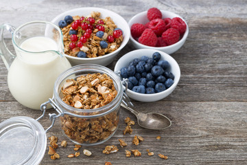 glass jar with granola, milk, and fresh berries on the wooden background