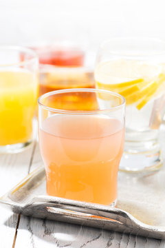 fresh citrus juices in glasses on white table, vertical