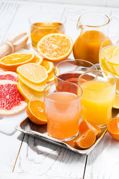 fresh citrus juices on white table, vertical