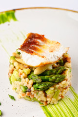 Fine dining, fish fillet breaded in herbs and spice on asparagus risotto.