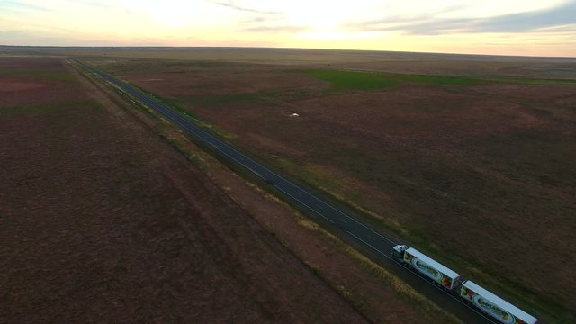 Aerial scene of outback highway or open road on dusk (sunset) with truck (lorry) (Semi-trailer) traveling on rural country high speed freeway. 
