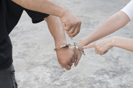 A man and woman's hands are handcuffed together