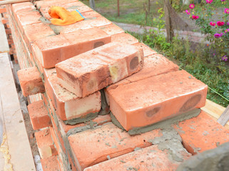 Bricklaying, Brickwork. Bricklaying on House Construction Site. Building Home wall from Bricks. Bricklayer Worker Installing Red Blocks and Caulking Brick Masonry Joints Exterior Wall.