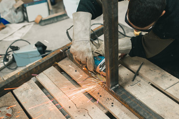 Man doing electroshooting of parts on the steel structure in the factory