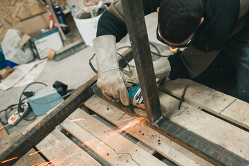 Man doing electroshooting of parts on the steel structure in the factory