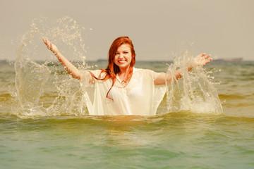 Redhead woman playing in water during summertime