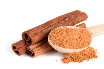 three cinnamon sticks and powder with spoon isolated on white background