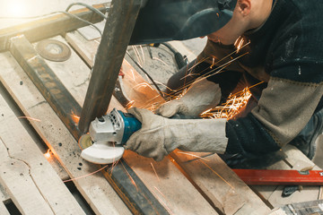 Man doing electroshooting of parts on the steel structure in the factory