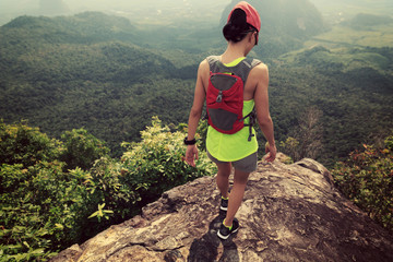 Obraz premium Young fitness woman trail runner running at mountain top