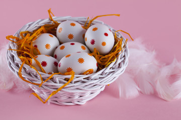 Easter eggs in the nest and basket on pink background