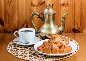 Cup of coffee, croissants and coffee pot on  table. Selective focus
