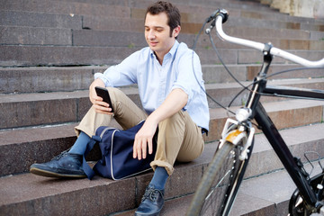 Fototapeta na wymiar Man is resting next to his bike and using phone