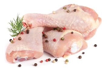 Three raw chicken drumsticks with a sprig of dill and peppercorns isolated on white background