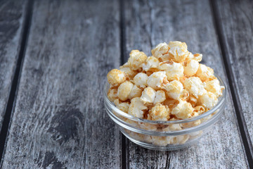 Popcorn in clear bowl on grey wooden plank table