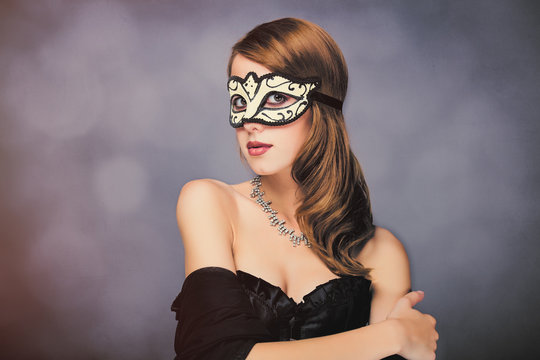 photo of beautiful young woman in mask on the wonderful black studio background