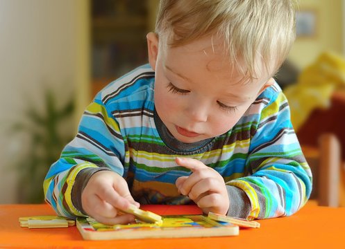 Little toddler doing puzzle. Boy learns to solve problems and develops cognitive skills and . Child concept.
