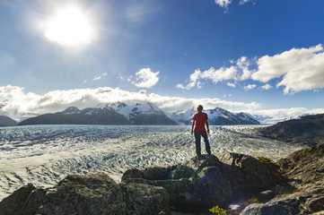 Naklejka premium man standing on the stone above Grey glacier in patagonia at sunset