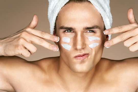 Young man with moisturizer cream on the face. Photo of man with perfect skin. Beauty & Skin care concept