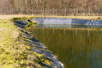 Landfill leachate pouring into pond from a black pipe. Location Ronneby, Sweden. - 143892908