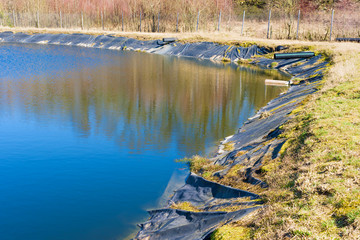 Leachate pond with synthetic lining and surrounding fence. Location Ronneby, Sweden.