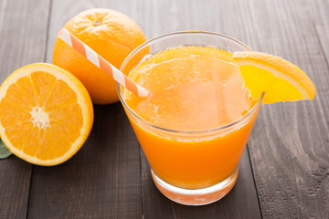 Fresh orange juice and oranges on wooden table