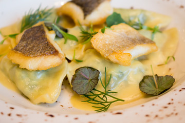 Ravioli with spinach and slices of fried fish Dorado