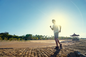 Sports lifestyle. Happy young african man jogging on the sea shore.