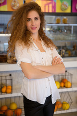 Portrait of smiling redhead waitress standing with arms crossed