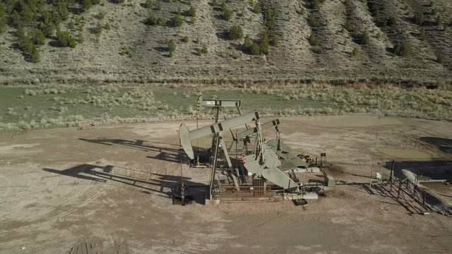 Aerial pair of industrial oil well pumps mountain valley. Industrial facilities to drill wells, extract and process crude oil and natural gas. Accidents and pollution spills damage environment.