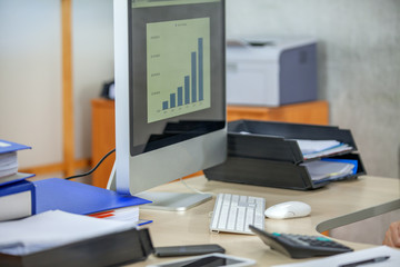 A blue chart is on the computer screen. A young businessman is working.