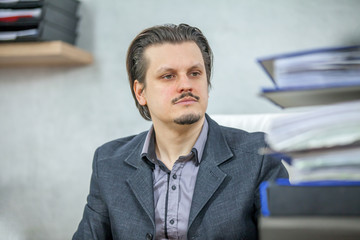 Obraz premium A young businessman is looking at the blue folders on his table.