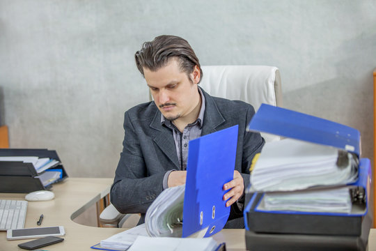 A businessman is checking the files and documents in the folder and he looks very focused.