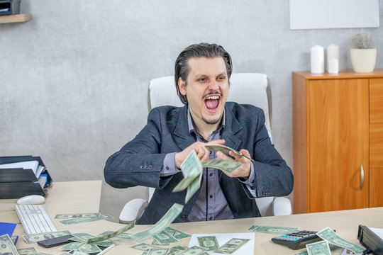 A happy businessman is having lots of money on the table. He is giving an expression of excitement.
