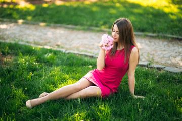 Fototapeta premium Beautiful girl posing to the photographer against the background of blooming pink trees. Spring. Sakura.