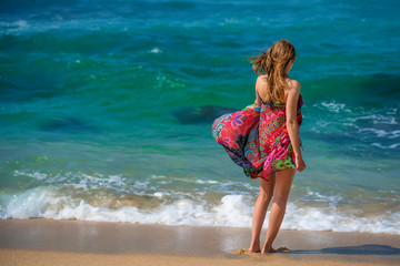 Beautiful young woman walking on ocean shore