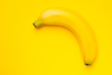 Single banana against yellow background