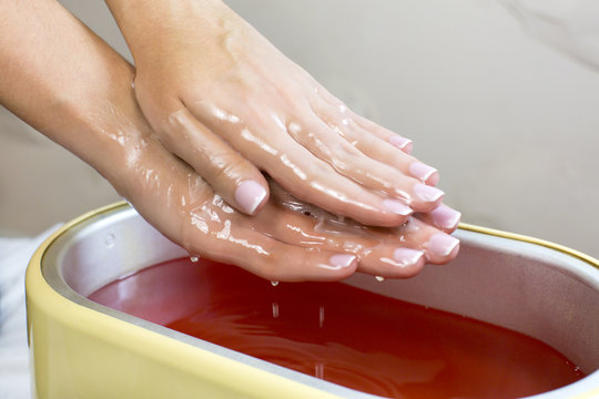 Process paraffin treatment of female hands in beauty salon 
