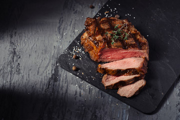 Sliced Steak of pork with rosemary on slate Board