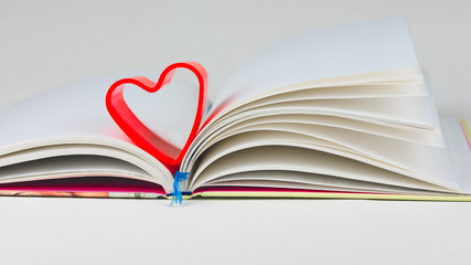 Red heart over diary book on white table