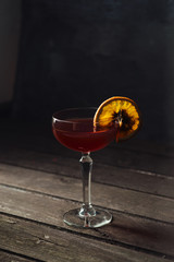 Hot mulled wine with slice of orange on a wooden table over dark background