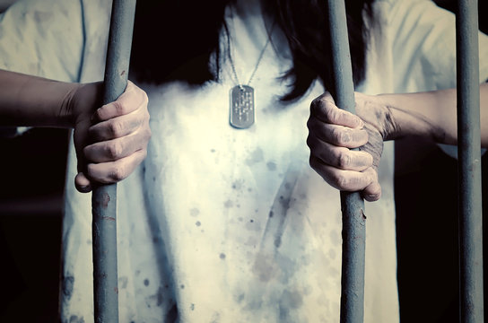 Donna che piega le sbarre di una prigione. Immagine astratta utilizzabile per concetti come evasione, diritti delle donne, disuguaglianza, rivincita, libertà.