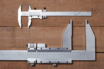 Carpenter tools on the wood table background. Big and small Vernier caliper 