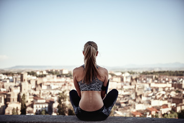 Fit girl relaxing in lotus pose after workout session outdoor in the evening. 