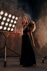 Portrait of beautiful attractive blonde young woman dancer on the stage with lights in loft background dancing free dance