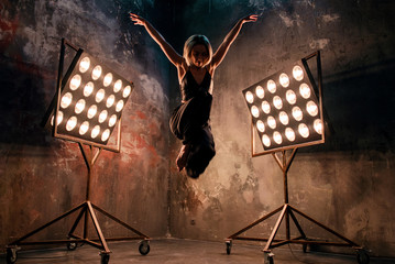 Portrait of beautiful attractive blonde young woman dancer on the stage with lights in loft...